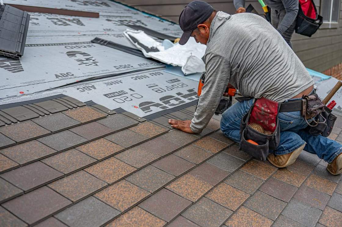 Roofer installing new asphalt shingles on a house