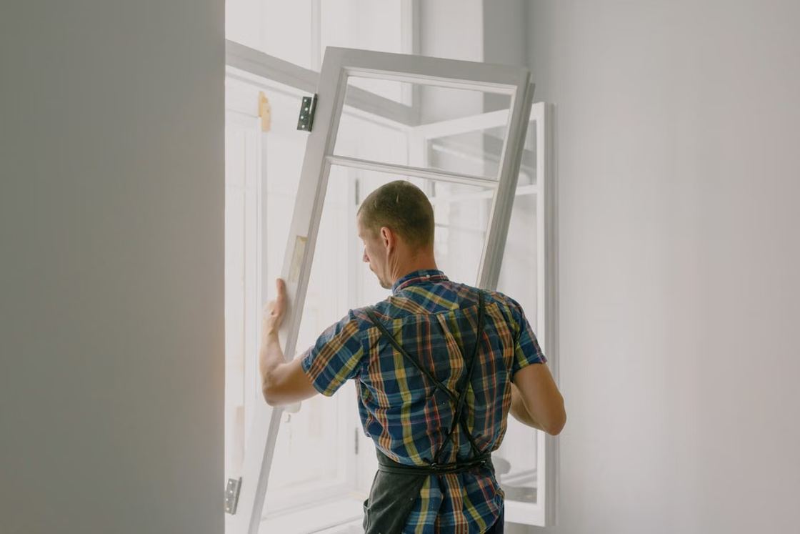 Installer fitting a new window frame in a bright room